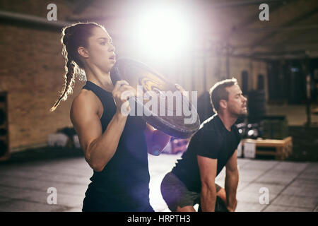 Sportlicher Mann und Frau mit Training mit schweren Gewicht Festplatten im geräumigen Fitnessraum runden. Stockfoto