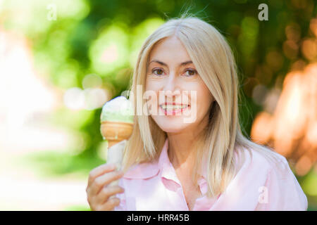 Glücklich Reife Frau Eis essen im park Stockfoto