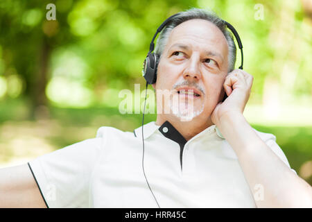 Mann Musik hören in einem park Stockfoto
