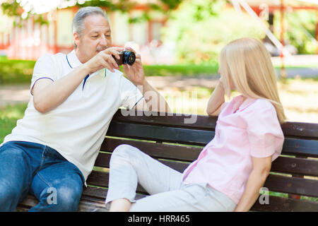 Älteres paar unter einem Selfie im Park auf einer Bank sitzend Stockfoto