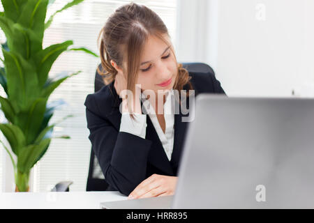 Junge Geschäftsfrau mit Schmerzen im Hals im Büro Stockfoto