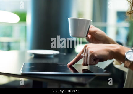 Detail einer Frau mit ihrem Tablet beim Kaffeetrinken Stockfoto