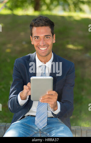 Junger Geschäftsmann mit seinem Tablettcomputer in einem park Stockfoto