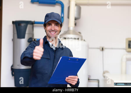 Lächelnde Techniker Wartung einer Warmwasser-Heizung Stockfoto