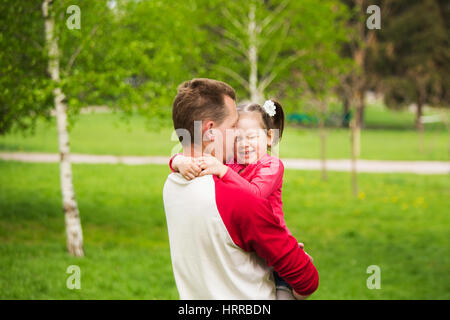 Closeup Portrait glückliche Familie. Kleine lustige Mädchen von 4 Jahren mit ihren Eltern im Stadtpark Frühling draußen spielen. Horizontale Farbfotografie Stockfoto