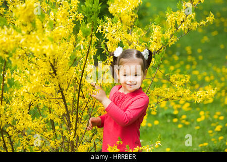 Süße lustige Mädchen vier Jahre alt in sonnige Stadt Frühlingspark fröhlich draußen spielen. Horizontale Farbfotografie. Stockfoto