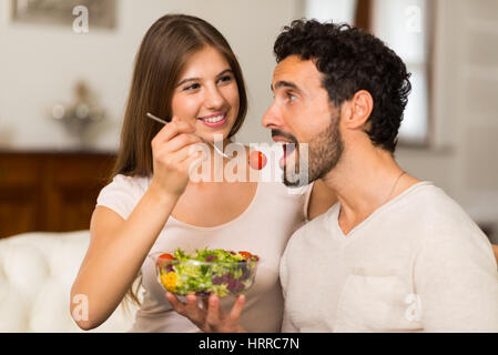 Paar im Wohnzimmer einen Salat zu essen. Geringe Schärfentiefe, die Frau im Mittelpunkt Stockfoto