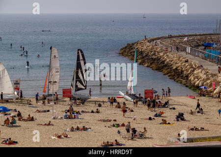 TEL AVIV - 7. April 2015: Der Strand von Tel Aviv, vollgepackt mit Menschen an einem heißen Tag. Einige sind im Wasser, einige sind Sonnenbaden oder im Schatten, Wohnung, auf A Stockfoto