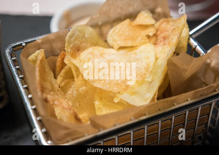 Detail der tiefe gebratene Chips serviert in einem metallischen Friteuse Korb Stockfoto