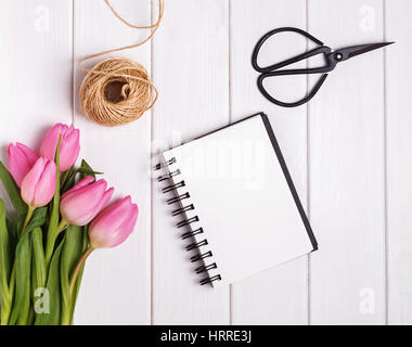 Rosa Tulpen und leeren Notizblock auf dem Holztisch, Ansicht von oben. Frühling Thema Mock-up. Stockfoto