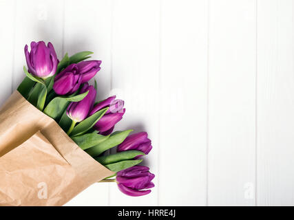 Rosa Tulpen eingewickelt in Papier Handwerk auf dem weißen Tisch, Ansicht von oben Stockfoto