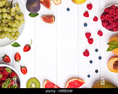 Vielzahl von Früchten und Beeren auf dem weißen Holztisch, Ansicht von oben Stockfoto