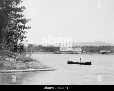 Mann im Kanu mit Saranac Inn im Hintergrund, oberen Saranac Lake, New York, USA, William Henry Jackson für Detroit Verlag, 1902 Stockfoto