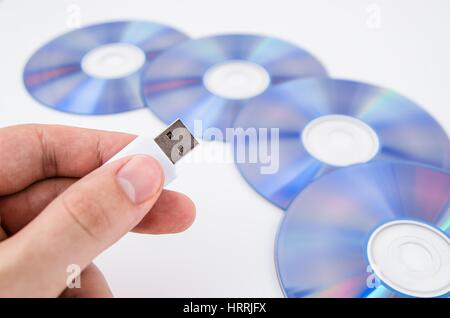 Hand mit USB-Laufwerk. DVDs im Hintergrund Stockfoto