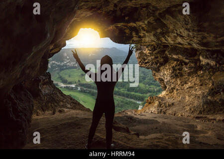 JUNGE FRAU STEHT ANHEBEN ARME SIEG HÖHLE FENSTER MIT BLICK AUF RIO GRANDE VALLEY DE ARECIBO PUERTO RICO Stockfoto