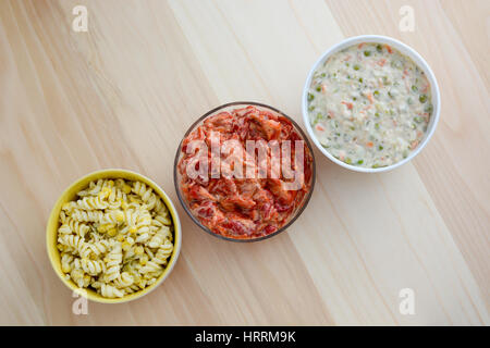 Nudelsalat, Paprikasalat und russischen Salat in Keramikschalen isoliert auf Holztisch mit Textfreiraum Stockfoto