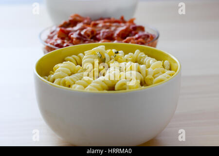 Nudelsalat, Paprikasalat und russischen Salat in Keramikschalen isoliert auf Holztisch. Stockfoto