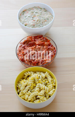 Nudelsalat, Paprikasalat und russischen Salat in Keramikschalen isoliert auf Holztisch. Stockfoto