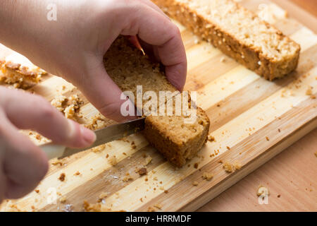 Weibliche Hände schneiden und vorbereiten Kuchen Kruste auf Holzplatte Stockfoto