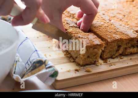 Weibliche Hände schneiden und vorbereiten Kuchen Kruste auf Holzplatte Stockfoto