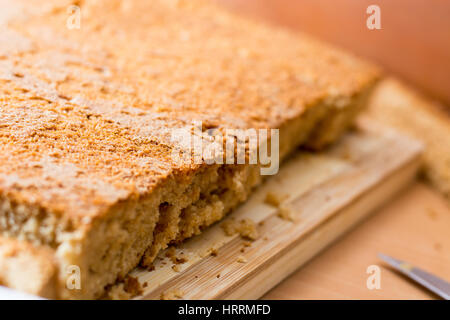 Weibliche Hände schneiden und vorbereiten Kuchen Kruste auf Holzplatte Stockfoto