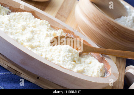 Geschmolzener Käse, vorbereitet für den Käsekuchen in der Holzschale mit Löffel Stockfoto