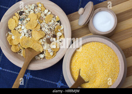 In einer kleinen hölzernen Schüssel platziert auf der Holzplatte mit Getreide und Mais Mehl Salz Stockfoto