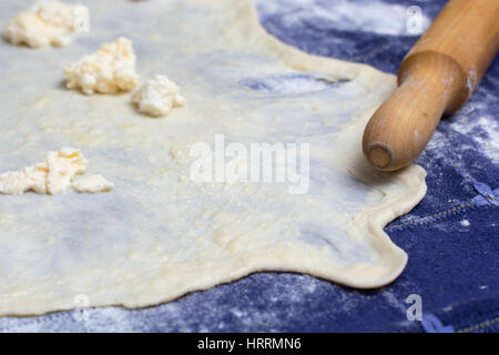 Hausgemachte Phyllo oder Strudel Teig mit Käse und Nudelholz auf einer home Tischdecke für Burek Käsekuchen oder andere Art von traditionellem Gebäck bereit. Stockfoto