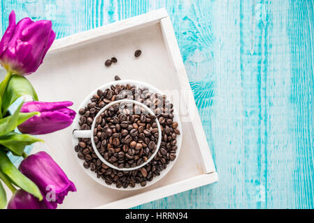 Vintage Holztablett mit Porzellantasse mit Kaffeebohnen und rosa Blumen auf shabby chic Minze Hintergrund, Ansicht von oben Stockfoto