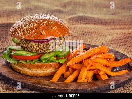 Vegetarische Burger mit frischem Gemüse und Süßkartoffel-Chips auf Holzplatte Stockfoto