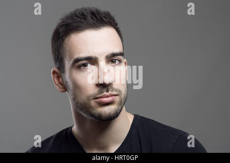 Nahaufnahme launisch Porträt skeptisch Stoppeln Mannes Blick in die Kamera über dunkle graue Studio-Hintergrund Stockfoto