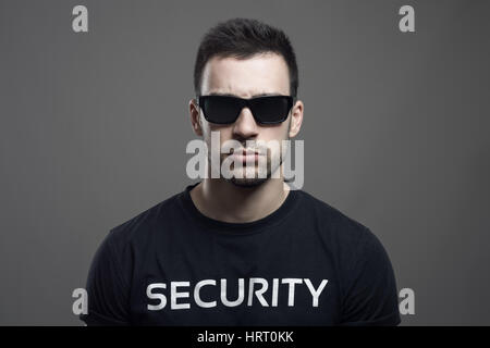 Ernsthafte launisch Porträt der Wachmann mit Sonnenbrille, Blick in die Kamera über dunkle graue Studio-Hintergrund. Stockfoto