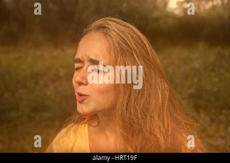 Blonde kurzhaarige Mädchen Grimasing und wegschauen mit ihren Augen geschlossen Retro-Farbbild. Stockfoto