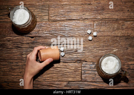 Beim Würfelspiel auf einem alten Holztisch mit Bierkrug Stockfoto