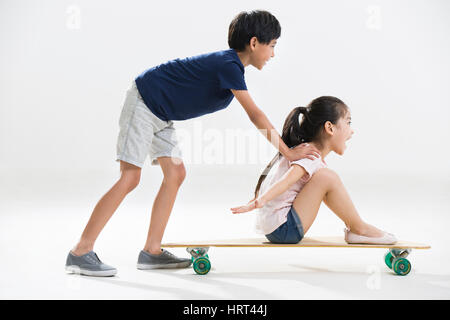 Niedliche kleine Jungen und Mädchen spielen mit skateboard Stockfoto