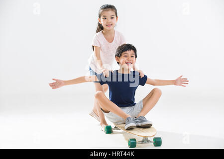 Niedliche kleine Jungen und Mädchen spielen mit skateboard Stockfoto