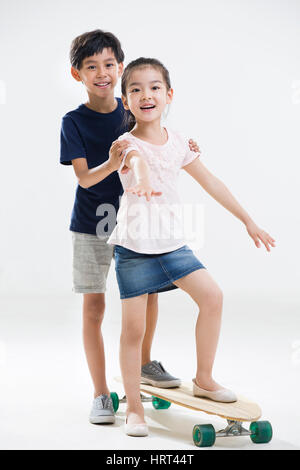 Niedliche kleine Jungen und Mädchen spielen mit skateboard Stockfoto