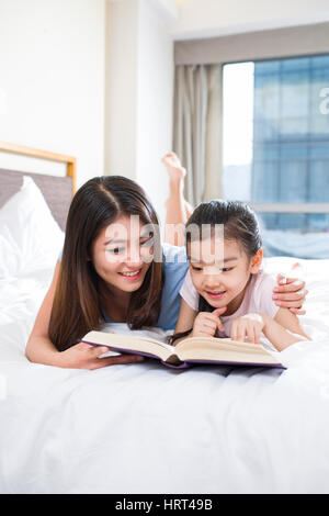 Kleines Mädchen, ein Buch zu lesen, mit Mutter Stockfoto