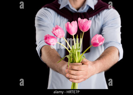 Close-up Teilansicht des Mannes präsentiert schöne rosa Tulpen auf schwarz, internationalen Frauen Tag Konzept Stockfoto