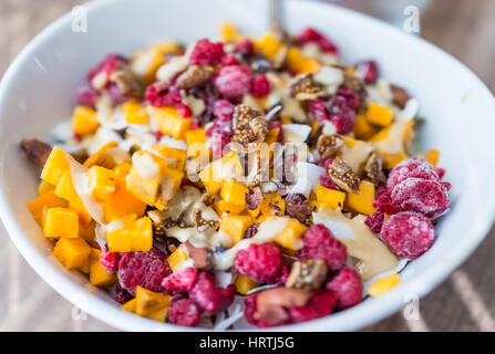 Gehackte Persimmon, Himbeeren und Feigen in Schüssel mit Tahini Makro Nahaufnahme Stockfoto