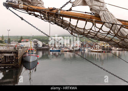 Husavik, Island - bunte Fischerboote vertäut am malerischen Hafen bei gedämpftem Licht Stockfoto