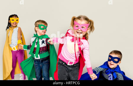 Kleine Kinder kleiden Superhelden an den Händen halten Stockfoto