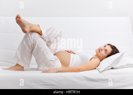 Junge schwangere entspannend auf sofa Stockfoto