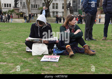 Frauen auf dem Rasen sitzen und Zeitung lesen, während der Demonstration stoppen Trump & Stop Brexit in Parliament Square, London. Stockfoto