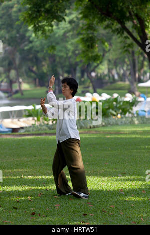 Im Lumphini Park, einer Erwachsenen Thai Frau praktizieren Tai-Chi-Chuan - Form einer chinesischen spannungsarmen Ausbildung - in den frühen Morgenstunden (Bangkok - Thailand). Stockfoto