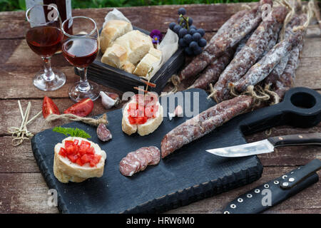 geschnittenem Brot, Tomaten und Wurst für Bruschetta auf Holzbrett. Stockfoto