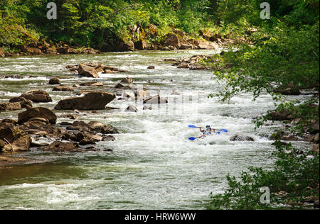 zwei Menschen schweben in einem Kanu mit Rudern auf einem Bergfluss Stockfoto