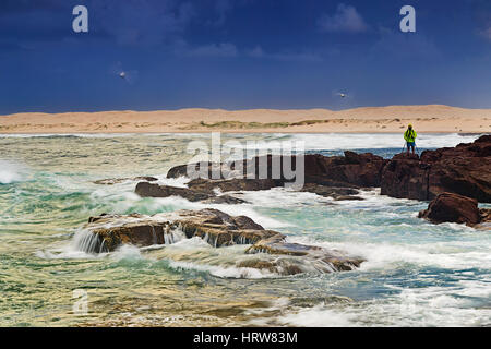 Stürmischer Sonnenaufgang am Felsstrand mit unscharfen Möwen fliegen in blauen Wolkenhimmel über Stockton Beach Sanddünen in New South Wales, Australien. Stockfoto