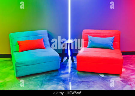 Ein paar bunte weichen Sofas in der Lounge mit Beistelltisch für Komfort der wartenden Kunden. Neon Lichter hinzufügen Multicolour Beleuchtung moder Stockfoto