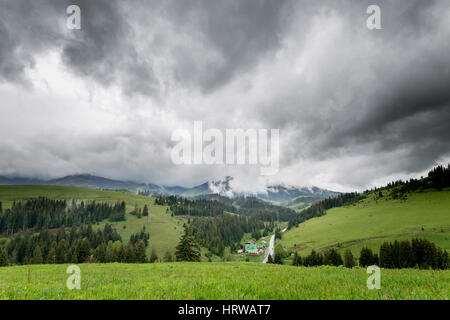 Gewitterwolken über die Berge und grüne Wiesen. Stockfoto